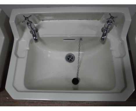 Three cream ceramic wall sinks, with taps