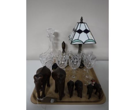 A tray containing six carved hardwood elephants, decanter, wine glasses, brass hand-bell, Tiffany style table lamp with shade