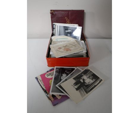A tin of monochrome photos, vintage postcards, leather autograph album (empty)