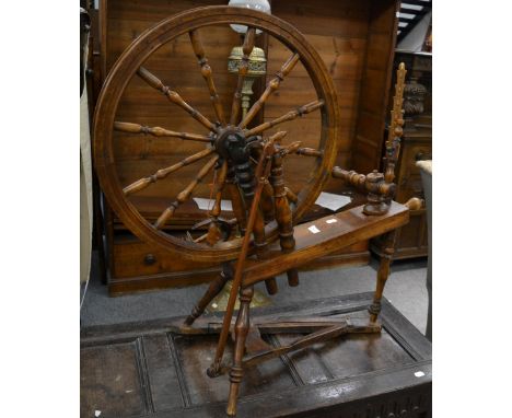 A 19th century pine and fruitwood spinning wheel, the bobbin turned wheel raised on four turned supports and platform base, m