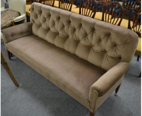 A late 19th century sofa, upholstered in buttoned back velvet, the overstuffed seat raised on square tapering legs with brass