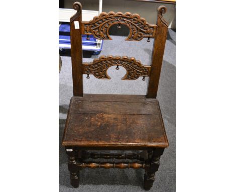 An oak joined backstool, circa 1700, with double crescent carved back support above a boarded seat, with bobbin turned stretc