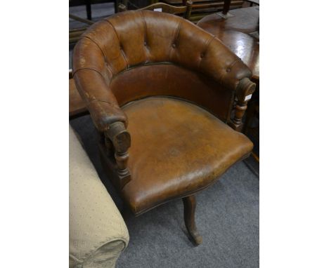 A 19th century oak framed swivel armchair upholstered in brown button back leather, the serpentine shaped overstuffed seat ra