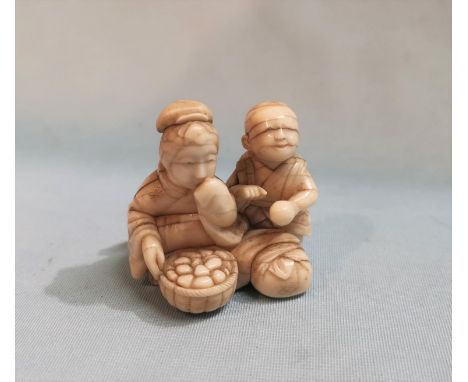 A late 19th / early 20th century Japanese carved Ivory Netsuke depicting a boy and a girl eating.