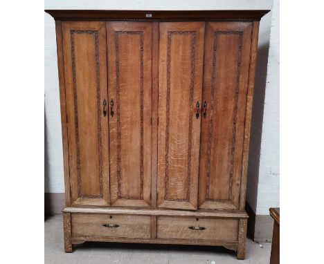 An early 20th century oak Arts & Crafts wardrobe by Arthur W Simpson of Kendal, with lines of carved decoration depicting ent