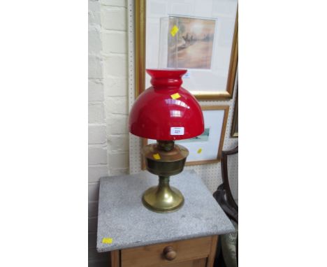 An Edwardian brass paraffin lamp, with red glass diffuser