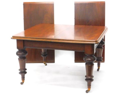 A Victorian mahogany extending dining table, the rectangular top with a moulded edge on turned and carved legs with ceramic c