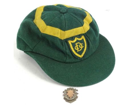 An early 20thC cricket cap, in green with gold band, the badge with monogram DCC and a silver fob for the Nottinghamshire and