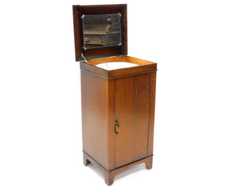 An oak wash stand cabinet, the hinged top enclosing a mirror and an enamel wash bowl with plug, etc., the door with further f