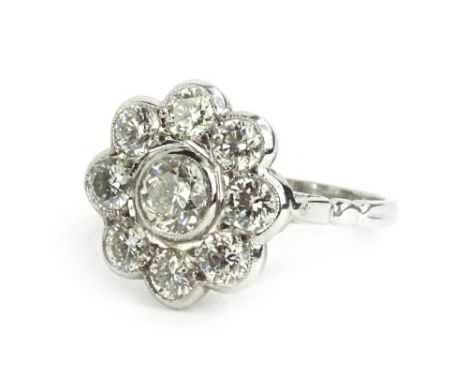 An Art Deco style diamond daisy ring, formed with round brilliant cut diamonds, in rub over setting, the central diamond appr