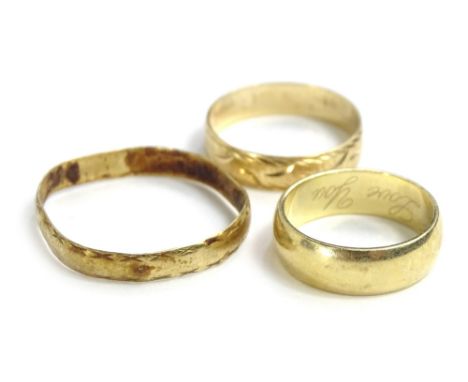 Three 9ct gold wedding bands, to include one of plain design, another with etched design and another large and misshapen, 7.4