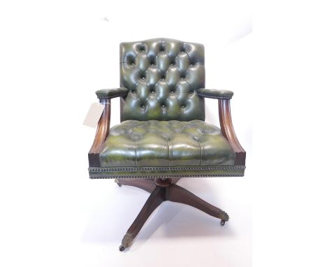 A 20th century mahogany desk chair, with green leather button back upholstery, raised on castors 
