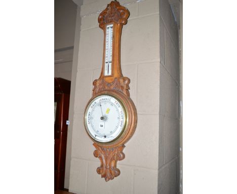 An aneroid barometer and mercury thermometer in ornately carved and stained oak banjo pattern mount (barometer pointer detach