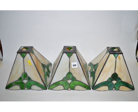 A set of three square tapering Tiffany style light shades in cream and green.