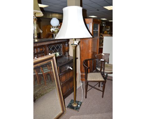 A modern brass corinthian column style standard lamp with cream coloured shade.