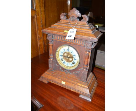 A Victorian mantel clock in architectural style oak case, the circular roman dial on blue and cream ground.