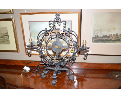 A wrought iron clock/table lamp, with circular arabic dial, see through dial, and two sconces for electric light bulbs (no sh