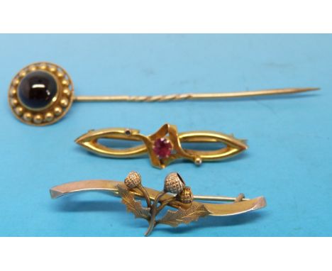 A 9ct gold brooch set with a ruby, 9ct gold thistle brooch and a Victorian stick pin set with a garnet cabochon