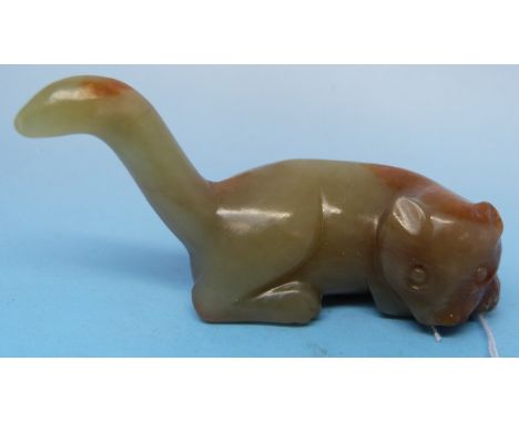 A Chinese jade carving of a recumbent cat with tail raised and russet inclusions (7.2cm wide)