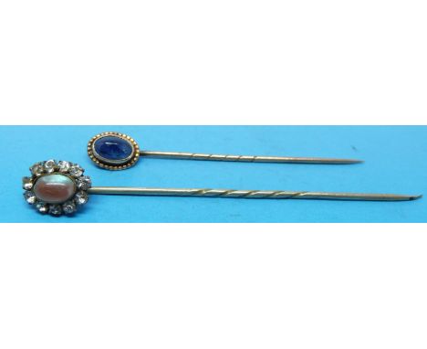 Two yellow metal stick pins, one set with a blue stone and the other a moonstone 