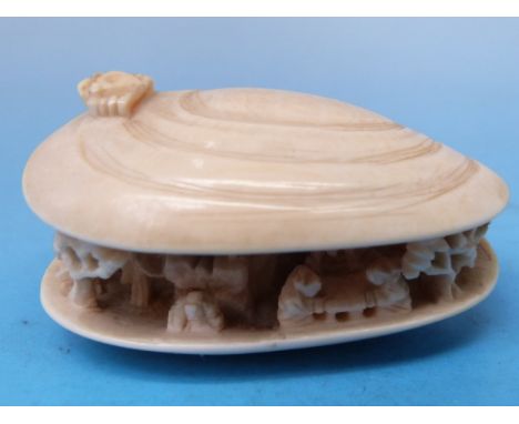 A carved Chinese ivory netsuke in the shape of an open shell with carved detail within