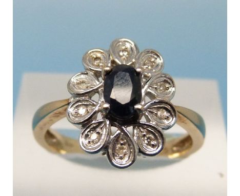 An 18ct gold ring set with an oval cut sapphire surrounded by diamonds in a platinum setting (size P)