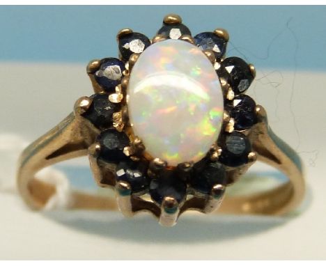 A 9ct gold ring set with an opal surrounded by sapphires (size L)