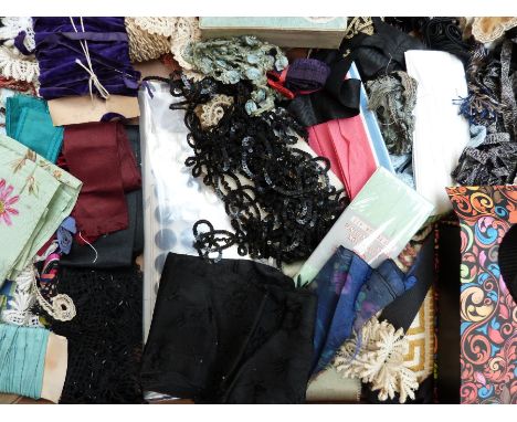 Two trays of vintage textiles including small rolls of silk, mourning belt, Art Deco bead choker and other beadwork