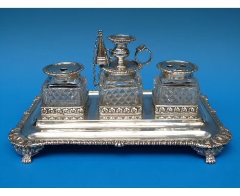 A Georgian hallmarked silver desk stand with three cut glass inkwells, small chamber stick and pen wells to base, (width of b