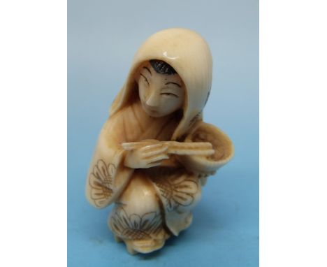 A Japanese ivory netsuke in the form of a geisha eating