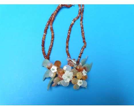 A necklace of jade, carnelian agate and mother of pearl arranged in a floral design  