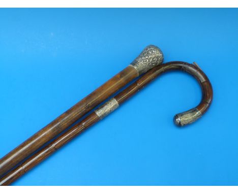 A white metal topped walking cane together with a hallmarked silver mounted walking stick 