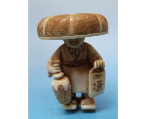 A Japanese ivory figural netsuke in the form of a man carrying a lantern