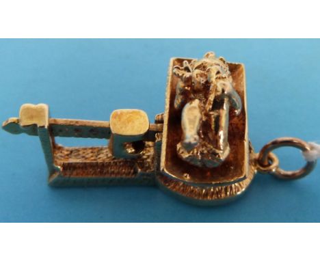 A 9ct gold charm in the form of a baby on scales with articulated mechanism and slide weight, London, marked 375 (6.6g)