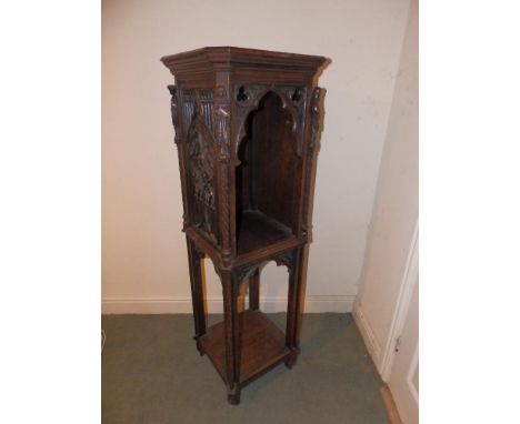 A 19thC Gothic Revival oak two tier stand, the upper tier with arched open front, each corner carved with a female saint, an 
