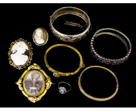 A late Victorian gold coloured metal mounted oval pattern mourning brooch, the glazed panel set with hair and seed pearl with