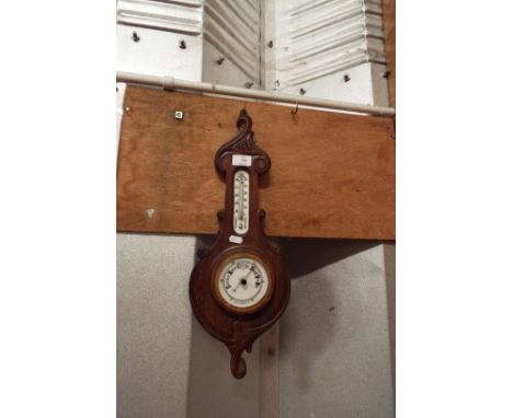 A floral carved oak aneroid barometer with thermometer above