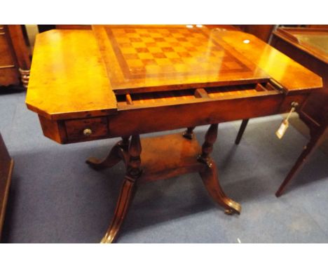 A 20thC burr walnut games table, the chequer board top opening to reveal a backgammon board and disc holders above four small