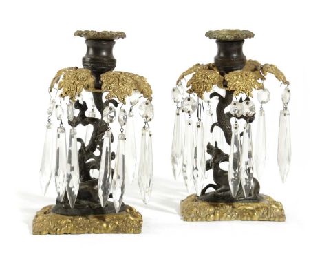 A PAIR OF REGENCY BRONZE LUSTRE CANDLESTICKSEARLY 19TH CENTURYeach modelled as a recumbent deer beneath a flowering tree with