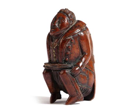 A COQUILLA NUT FIGURAL SNUFF BOX OF A MANPROBABLY FRENCH, LATE 18TH / EARLY 19TH CENTURYcarved as a man squatting behind a bu