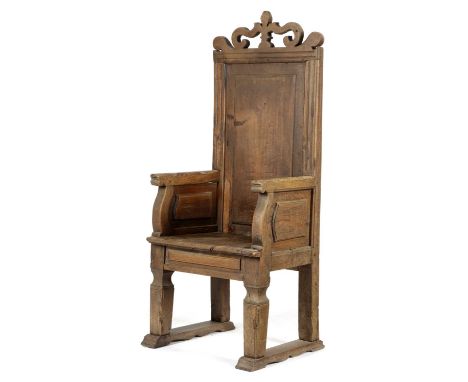 AN ITALIAN WALNUT ENCLOSED PANELLED BACK ARMCHAIRPOSSIBLY LOMBARDY, LATE 16TH / EARLY 17TH CENTURYwith a scroll cresting with