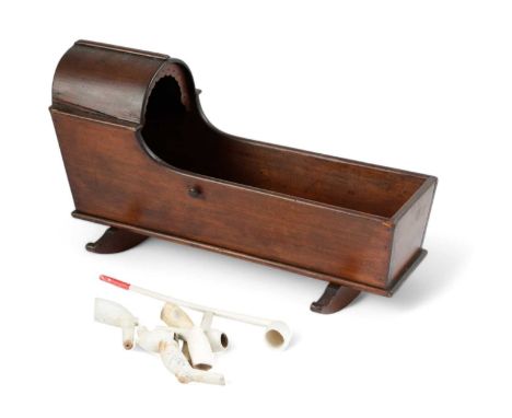 A VICTORIAN PINE CHURCH WARDEN'S PIPE CRADLELATE 19TH CENTURYthe hood with a pierced rim, on rockers, together with a clay pi