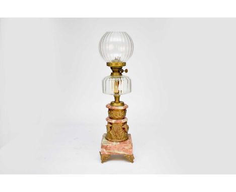 A gilt-metal and pink veined marble oil lamp, the ribbed clear glass globe shade and reservoir raised on a cast cylindrical s