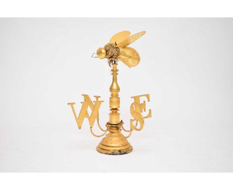 A novelty, contemporary gold coloured weather vane, with a bee finial, over a baluster support, above a revolving 'N', 'S', '