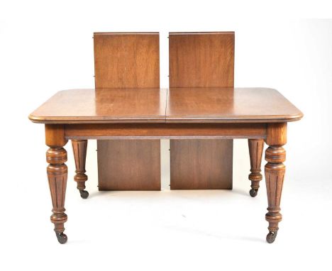 A Victorian oak telescopic extending dining table, with tapering, turned and fluted legs, terminating in porcelain castors, t