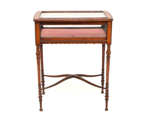 An Edwardian mahogany bijouterie table, the glazed top with beaded edge, raised on slender ring-turned supports united by an 