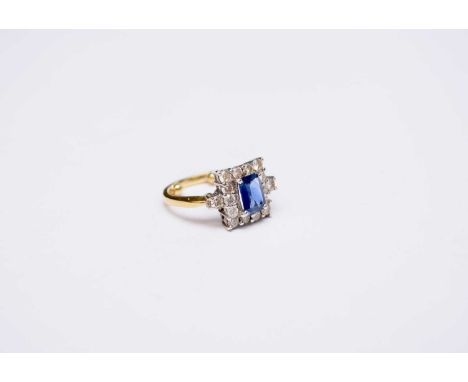 An 18ct gold sapphire and diamond ring, designed as a central square mixed cut sapphire claw set within a border of fourteen 