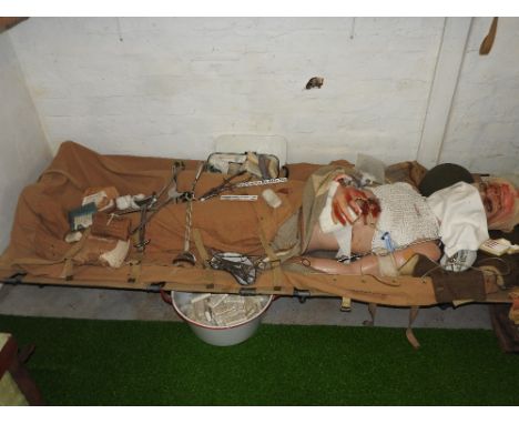 A field casualty mannequin on stretcher in a WWII stretcher bag by M Co circa 1944 along with a lidded enamel tin of dressing