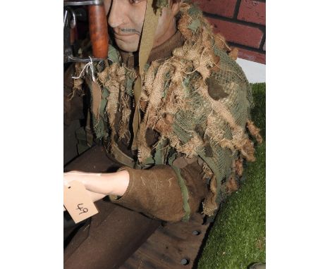 A seated mannequin in khaki with webbing, red beret and camouflage helmet