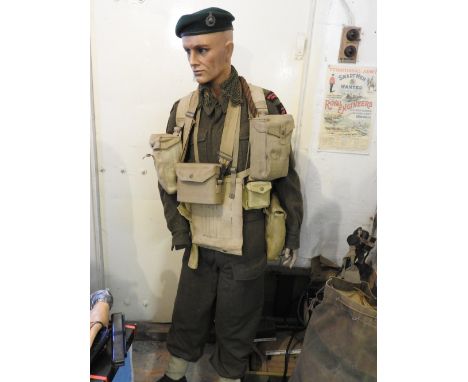 A standing mannequin wearing green beret, camouflage smock uniform with insignia for Royal Marines Commando with a quantity o